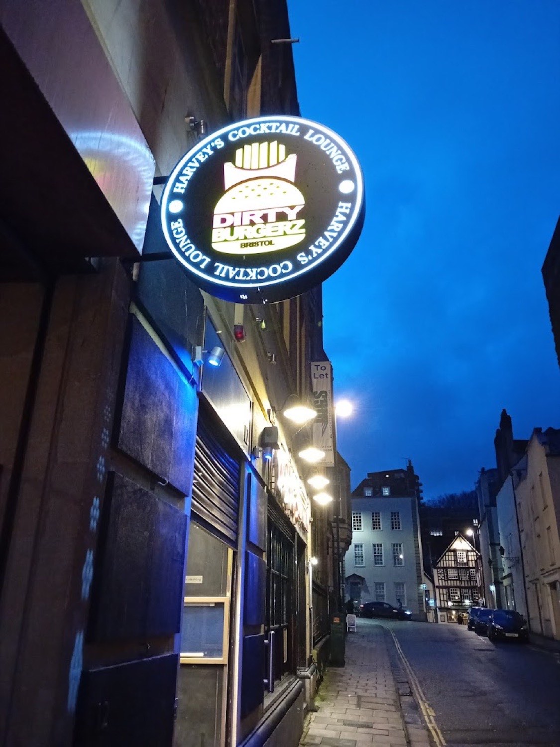 Illuminated projecting sign on a Bristol street at dusk